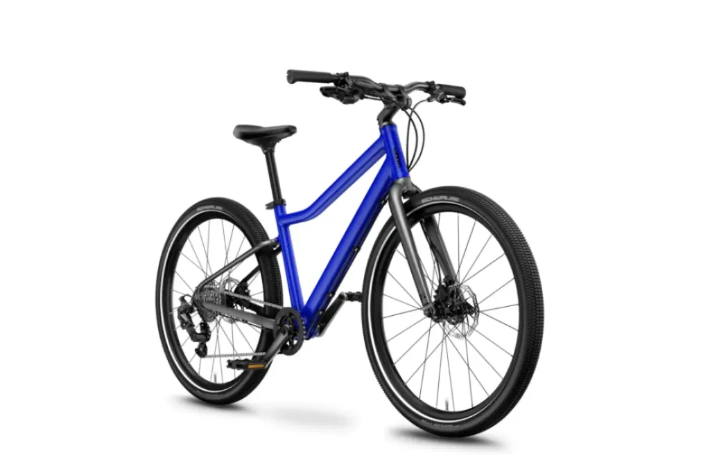 La WOOM 4 Explore es una bicicleta azul y negra que cuenta con frenos de disco, un cuadro de acceso bajo y neumáticos con tacos, que se muestran sobre un fondo blanco.