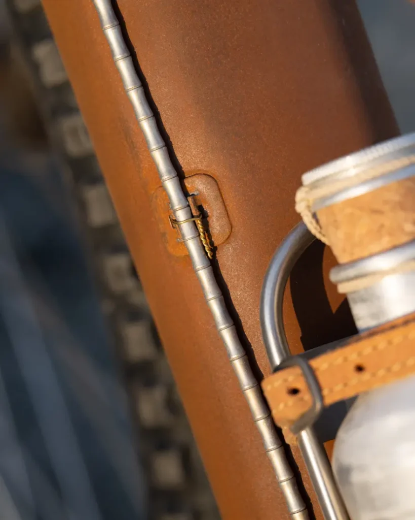 Un primer plano del cuadro de una bicicleta SCOTT Solace muestra indicios de óxido y un resistente portabotellas que sostiene una botella con tapa de corcho y evoca la esencia agreste del páramo.