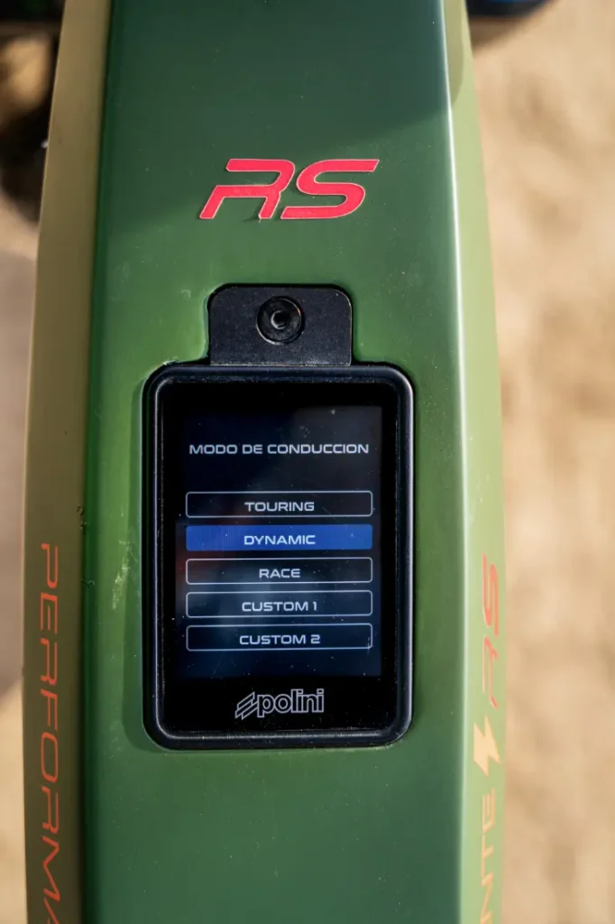 Primer plano de una pantalla de control en una motocicleta que muestra los modos de conducción: Touring, Dynamic, Race, Custom 1 y Custom 2. Esta potente motocicleta luce con orgullo las letras "RS" y "Performance" en el cuadro, lo que representa la verdadera potencia italiana similar al legado de la Polini E-P3+ MX.