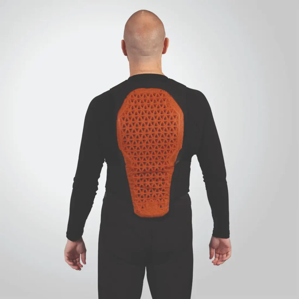 Una persona que viste un traje negro con un panel trasero protector texturizado de color naranja Endura.