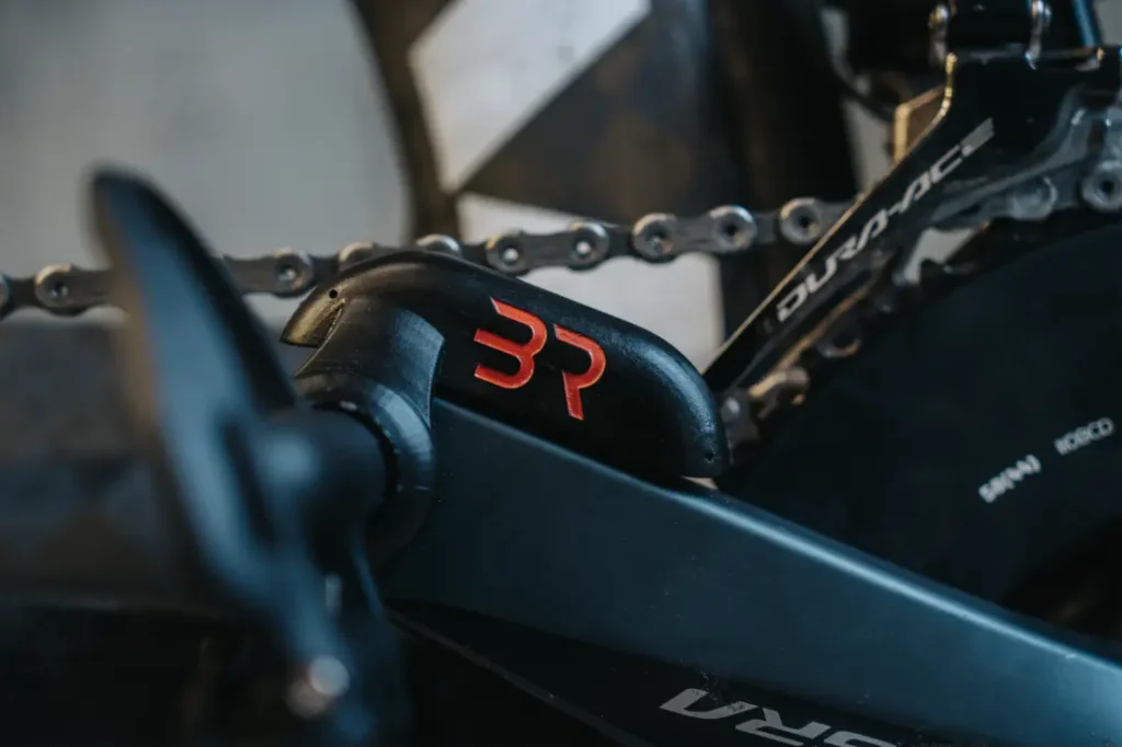 Primer plano de la transmisión y el desviador de una bicicleta con un logotipo "BR" rojo en un componente, integrando a la perfección el potenciómetro Body Rocket para un rendimiento óptimo.