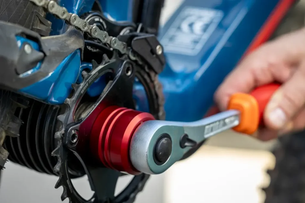 Una persona utiliza una llave de trinquete Unior para ajustar cuidadosamente el pedalier de una bicicleta.