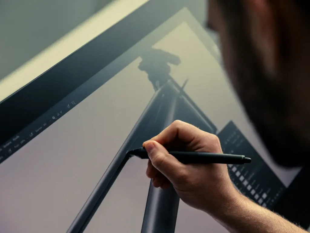 Una persona usa un lápiz digital para dibujar en la pantalla de una tableta, elaborando meticulosamente cada detalle del diseño del cuadro de la bicicleta UNNO MITH.