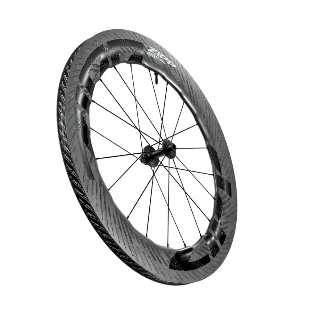 Una rueda de bicicleta de fibra de carbono Zipp 2026 con llantas aerodinámicas de sección profunda y radios negros, diseñada para rodar más rápido, mostrada sobre un fondo blanco.
