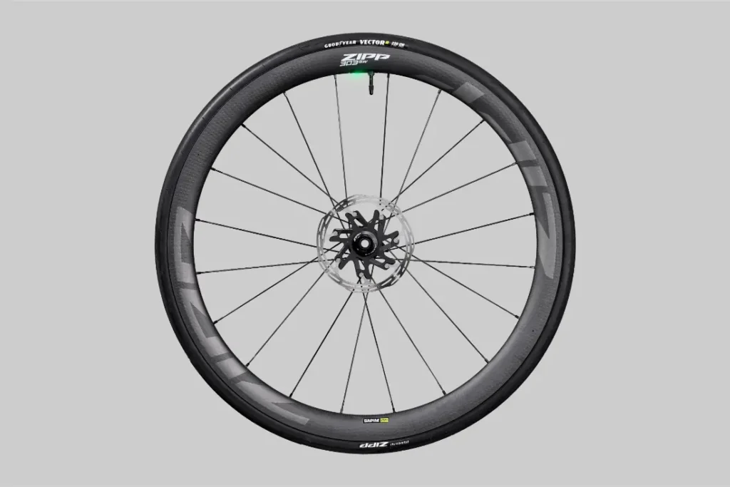 Se muestra una sola rueda de bicicleta Zipp 2026 negra con radios finos y un rotor de freno de disco sobre un fondo gris simple, diseñado para ayudarlo a rodar más rápido en cada recorrido.