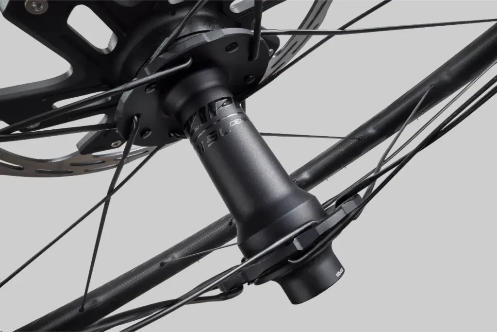Vista de cerca de un cubo de rueda de bicicleta Zipp 2026 con rotor de freno de disco y radios acoplados, fotografiado sobre un fondo gris simple, diseñado para rodar más rápido.