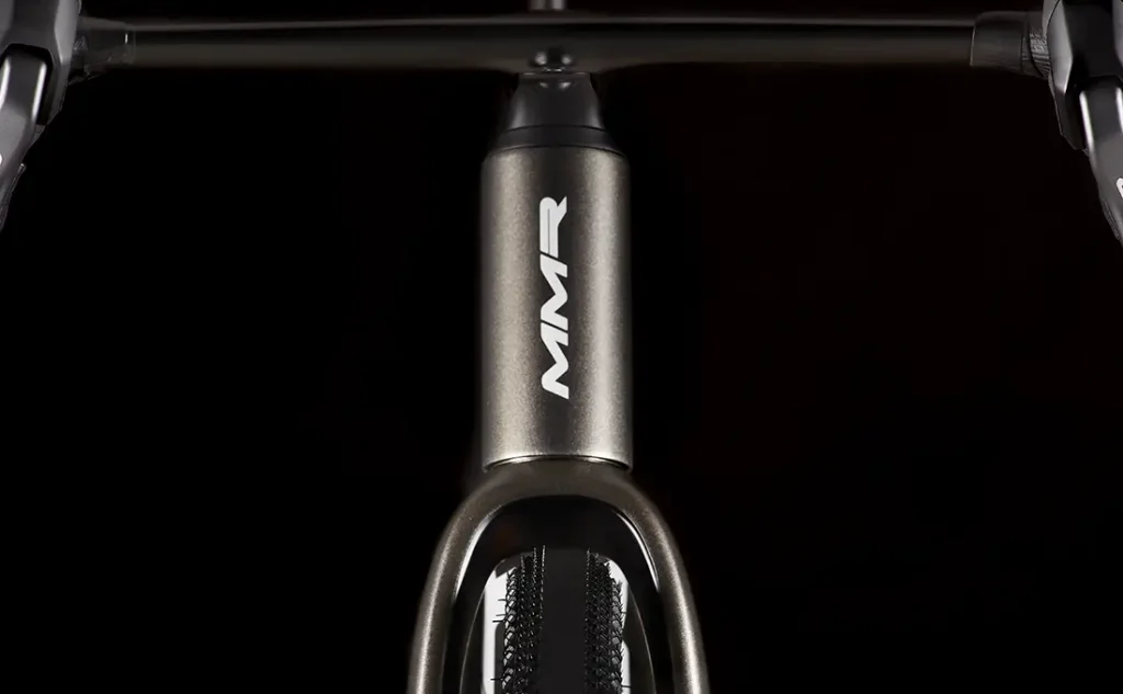Vista de cerca del tubo de dirección de una bicicleta con el logotipo "MMR Simun", con el manillar y el neumático delantero parcialmente visibles sobre un fondo negro.