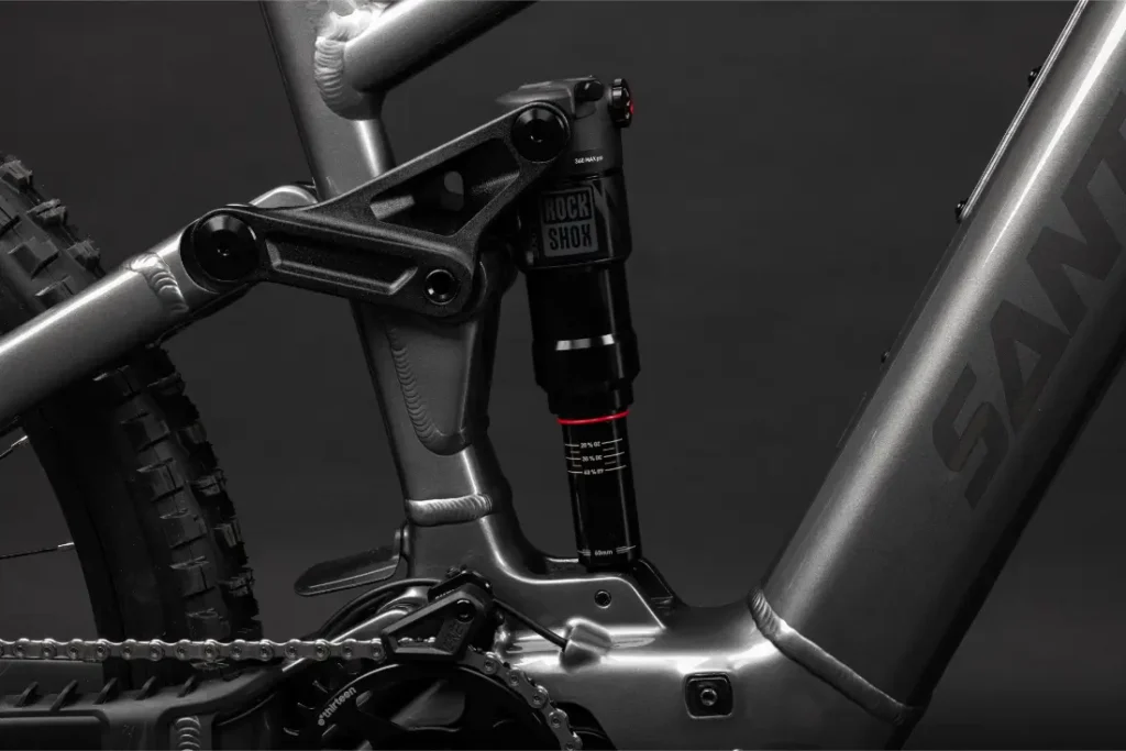 Primer plano de un cuadro de bicicleta Santa Cruz Vala AL de aluminio, centrado en el sistema de suspensión trasera con un amortiguador RockShox y componentes de cadena visibles.