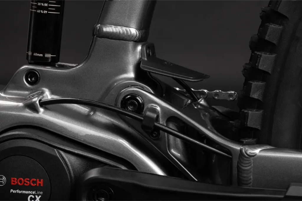 Primer plano de un motor Bosch Performance Line CX en una bicicleta eléctrica Santa Cruz Vala AL, destacando la zona de la rueda trasera, el cableado y el varillaje de la suspensión fabricados en robusto aluminio.