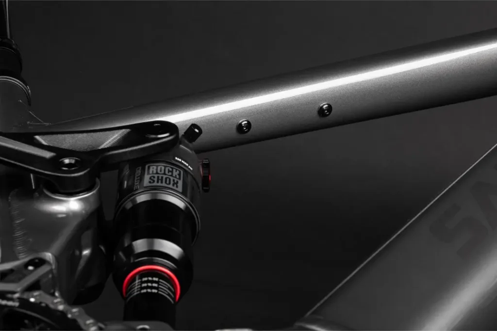 Primer plano de un cuadro de bicicleta Santa Cruz Vala AL en aluminio, destacando la suspensión trasera RockShox y parte de la bieleta sobre un fondo oscuro.