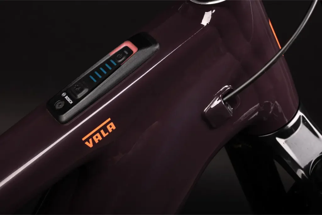 Primer plano de un cuadro de bicicleta Santa Cruz Vala AL fabricado en aluminio, con una pantalla digital y el nombre de la marca "VALA" en letras naranjas.