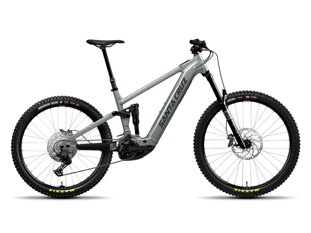 Bicicleta de montaña eléctrica Santa Cruz Vala AL gris con suspensión total, fabricada en aluminio, frenos de disco, neumáticos anchos y motor de tracción central visible, mostrada de perfil sobre fondo blanco.