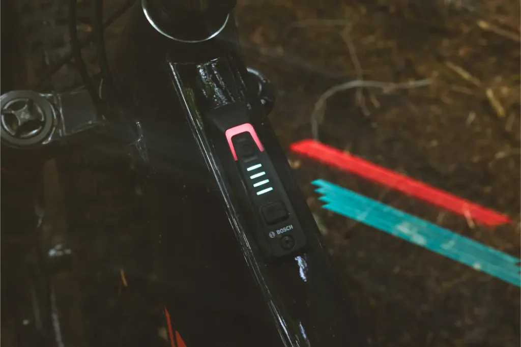 Primer plano de un panel de control Bosch e-bike montado en el cuadro de aluminio negro de una bicicleta Santa Cruz Vala AL, que muestra cinco barras indicadoras de batería iluminadas.