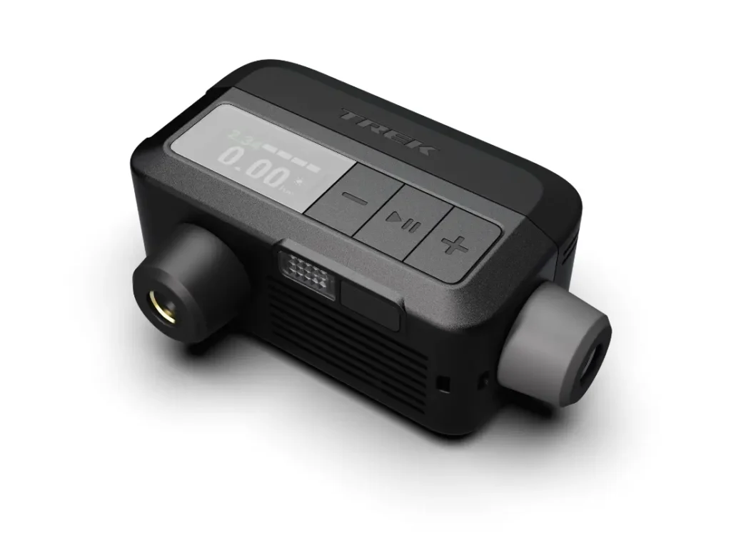 Dispositivo electrónico compacto y rectangular para inflado de ruedas con pantalla digital, botones y dos conectores, con la marca "Trek Air Rush" en la superficie superior.