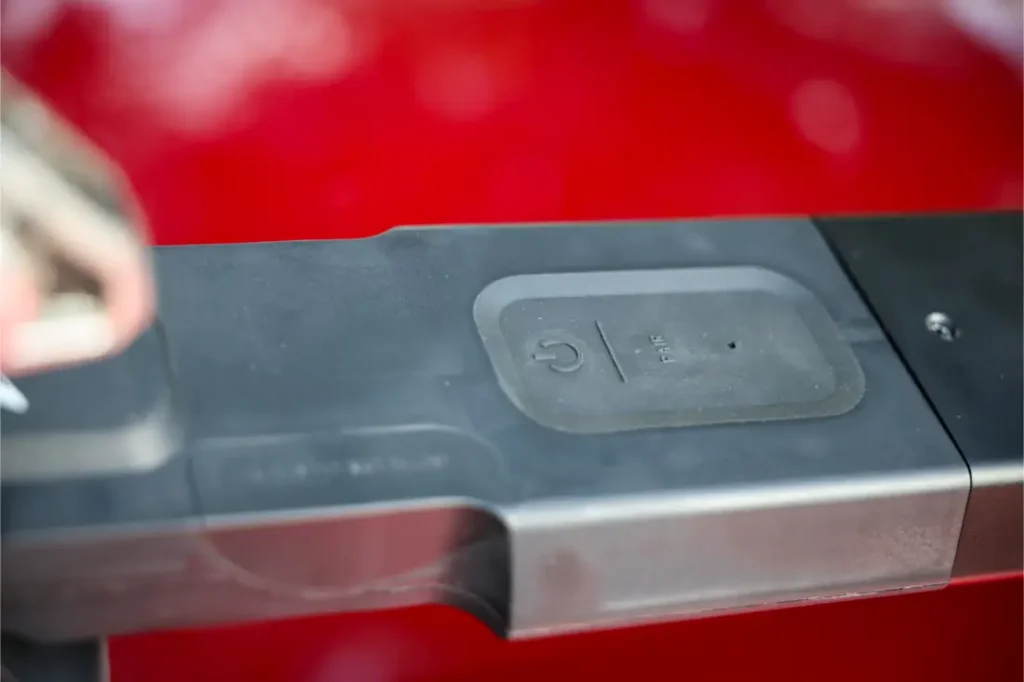 Primer plano de una cerradura electrónica con un botón de encendido y una llave cerca, con un fondo rojo difuminado, similar al diseño seguro e innovador del portabicicletas Allen Smart Suction.