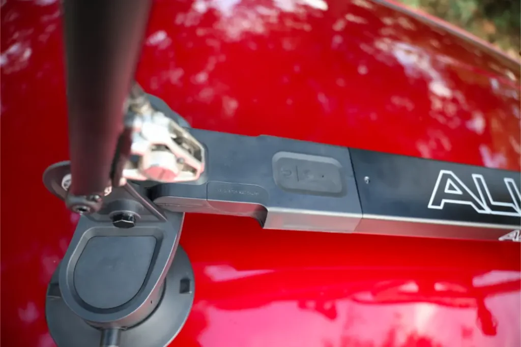 Primer plano de un portabicicletas Allen Smart Suction montado en el techo de un coche rojo brillante, en el que destaca el robusto mecanismo del portabicicletas y los pedales.