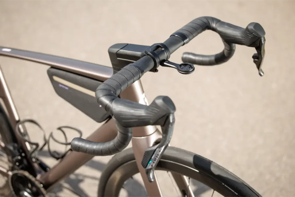 Primer plano del manillar de una moderna bicicleta de carretera SCOTT Addict, con cambios integrados, manillar aerodinámico, soporte para dispositivos montado en el manillar y bolsa de almacenamiento montada en el cuadro.