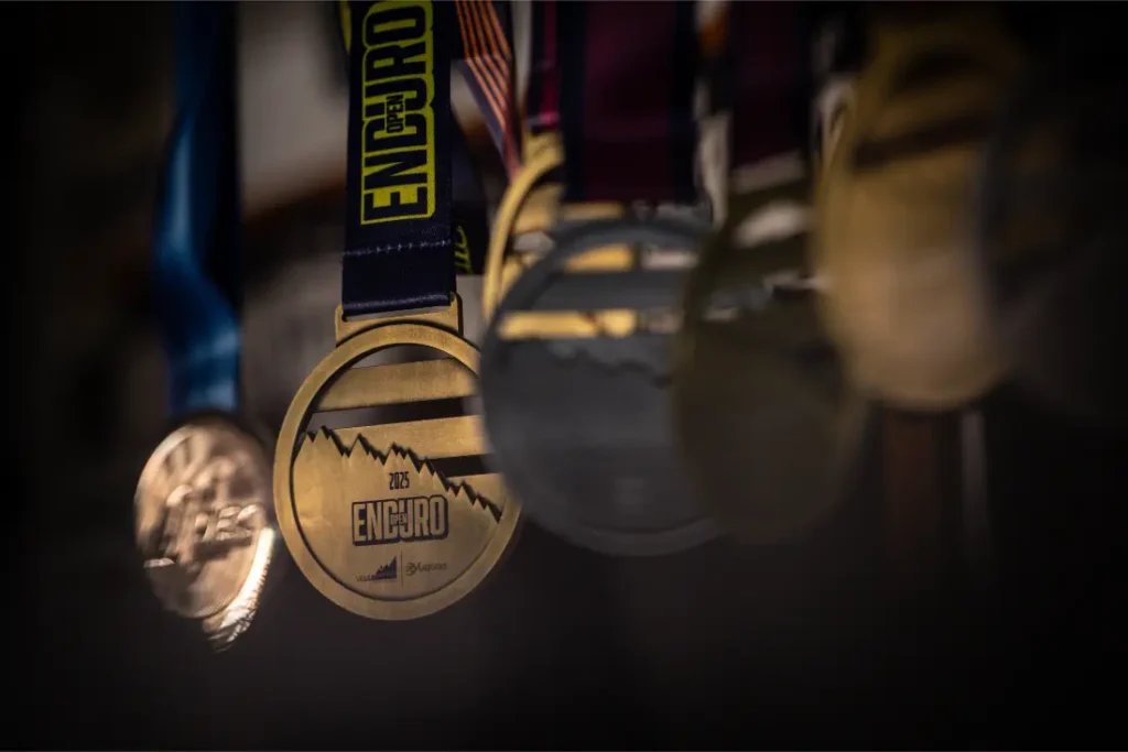Primer plano de varias medallas colgadas de cintas, con la medalla de oro central rotulada "ENDURO 2023" y un gráfico de montaña, como se ve en la entrevista a Jordi Bagó sobre sus logros.