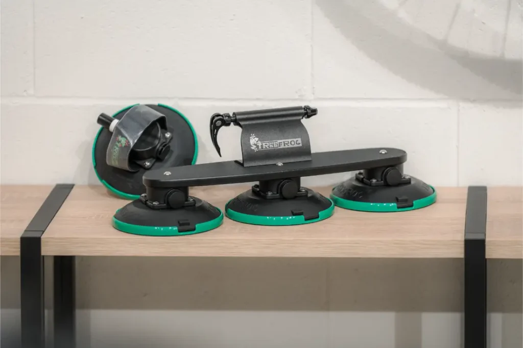 Una baca con ventosas Vic Sports con tres bases de ventosa de bordes verdes descansa sobre una mesa de madera contra una pared blanca.