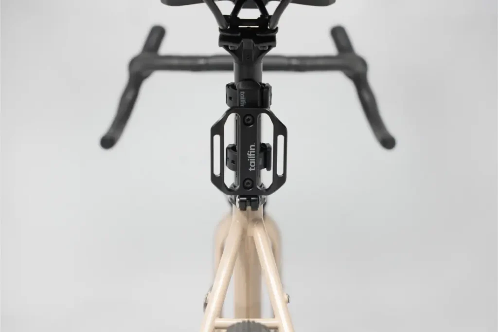 Vista desde arriba de la sección delantera de una bicicleta, mostrando el manillar, la potencia y un portaaccesorios de la marca Topeak montado en el tubo de dirección junto a un Tailfin Hydromount.