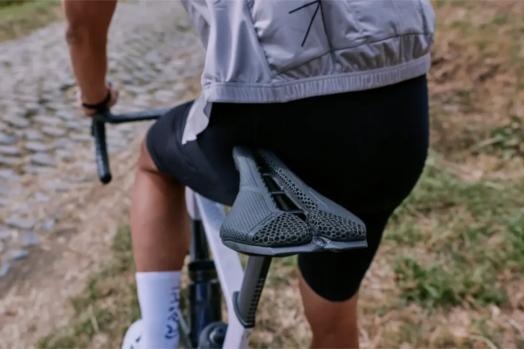 Un ciclista con chaqueta ligera y pantalón corto negro conduce una bicicleta con un moderno sillín PRO Stealth 3D por un camino empedrado.