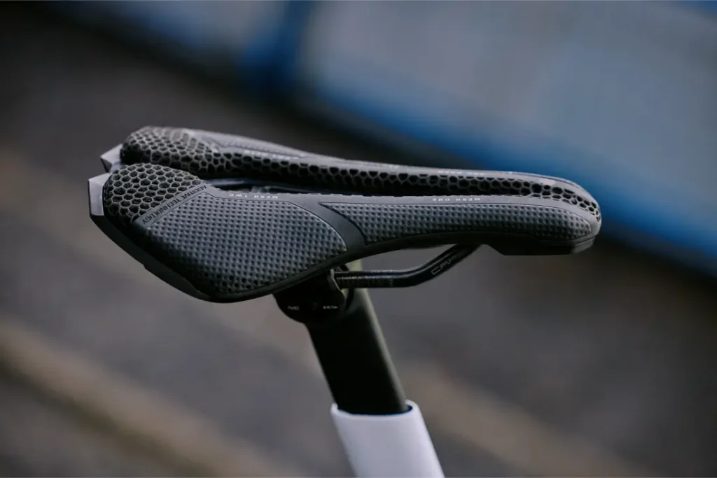 Primer plano de un sillín de bicicleta PRO Stealth 3D, negro y con diseño de panal, montado sobre una tija de sillín, con un fondo exterior difuminado.
