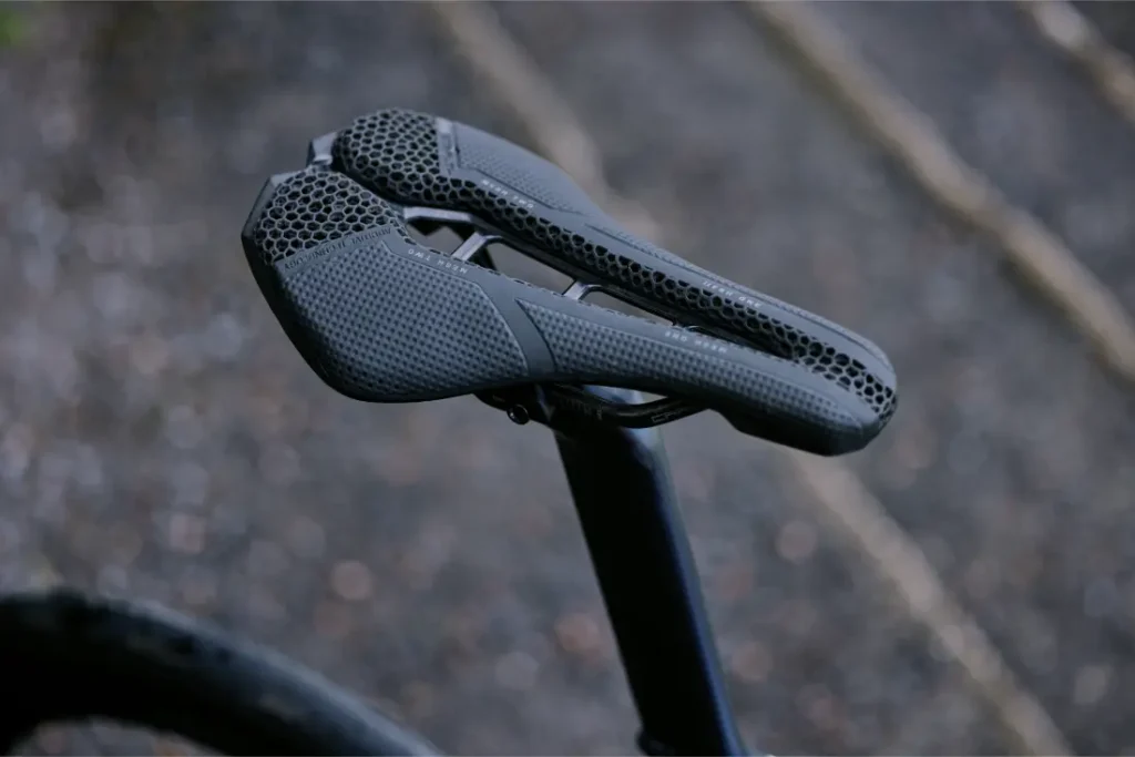 Primer plano de un moderno sillín de bicicleta PRO Stealth 3D de color negro con diseño de panal de abeja, montado en una tija de bicicleta.