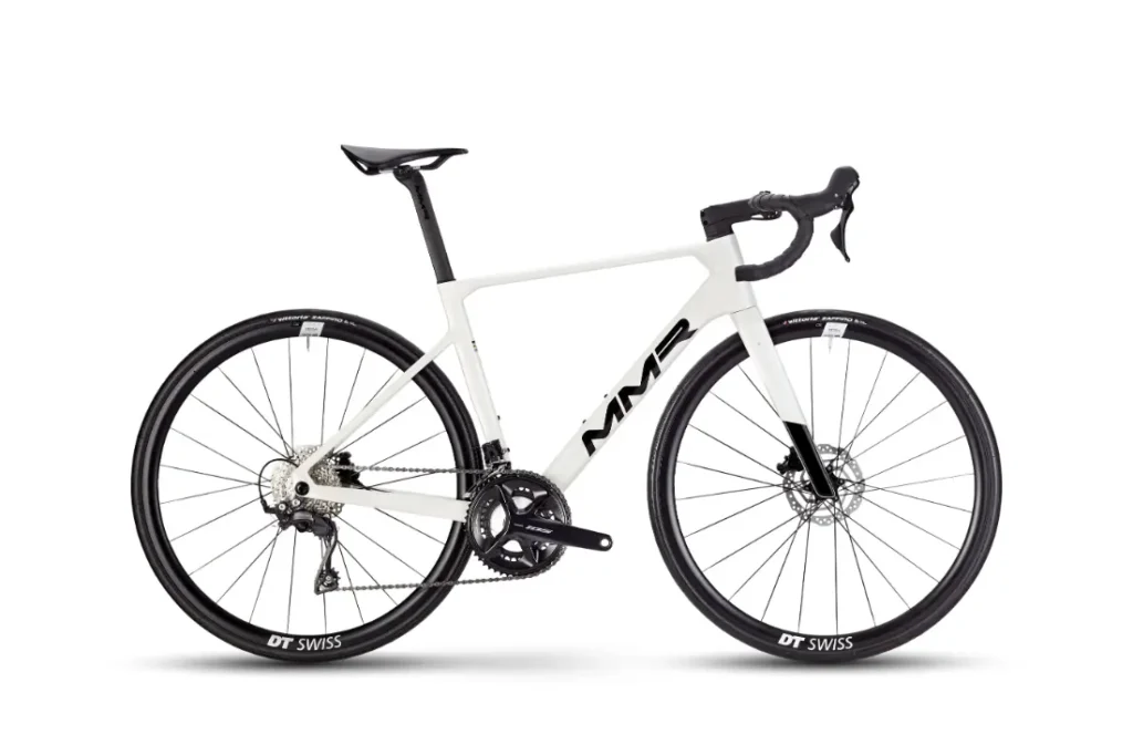 Una bicicleta de carretera MMR Aelion SL blanca con manillar rebajado, frenos de disco y ruedas DT Swiss negras se muestra de perfil sobre un fondo liso.