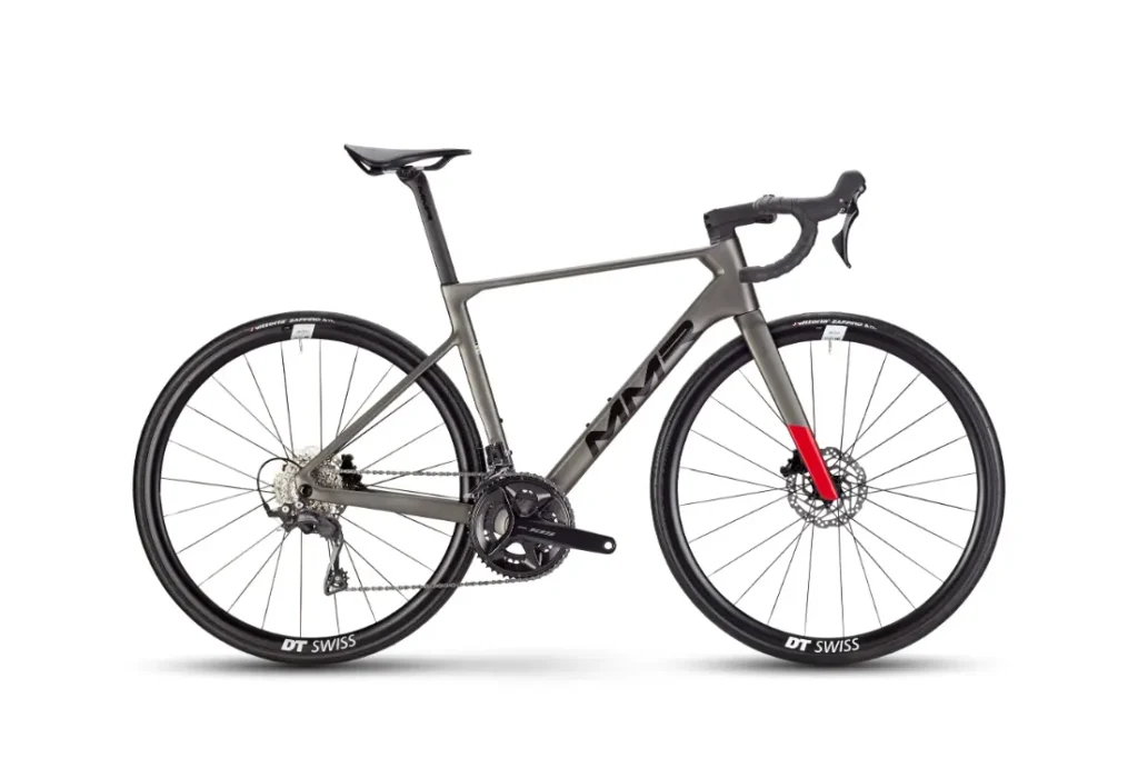 Vista lateral de una moderna bicicleta de carretera MMR Aelion con manillar rebajado, frenos de disco y ruedas DT Swiss, con un cuadro gris oscuro y un acento rojo en la horquilla delantera, perfecta para cualquier entusiasta de la bici total.