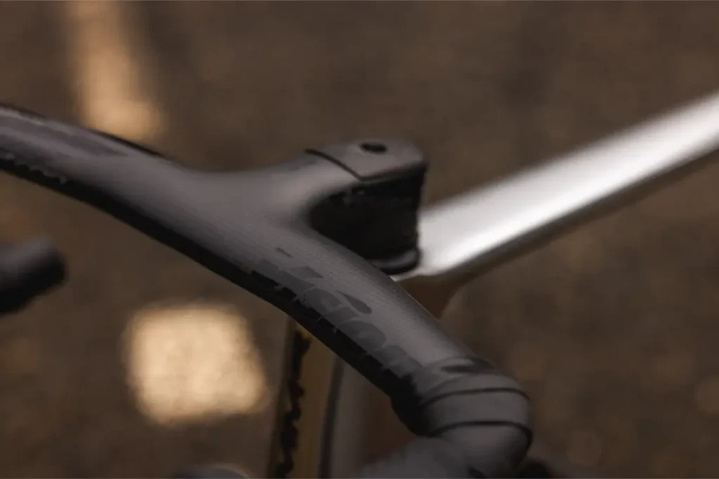 Primer plano de un manillar y una potencia de bicicleta negros, probablemente de una MMR Aelion SL, sobre un fondo marrón borroso.