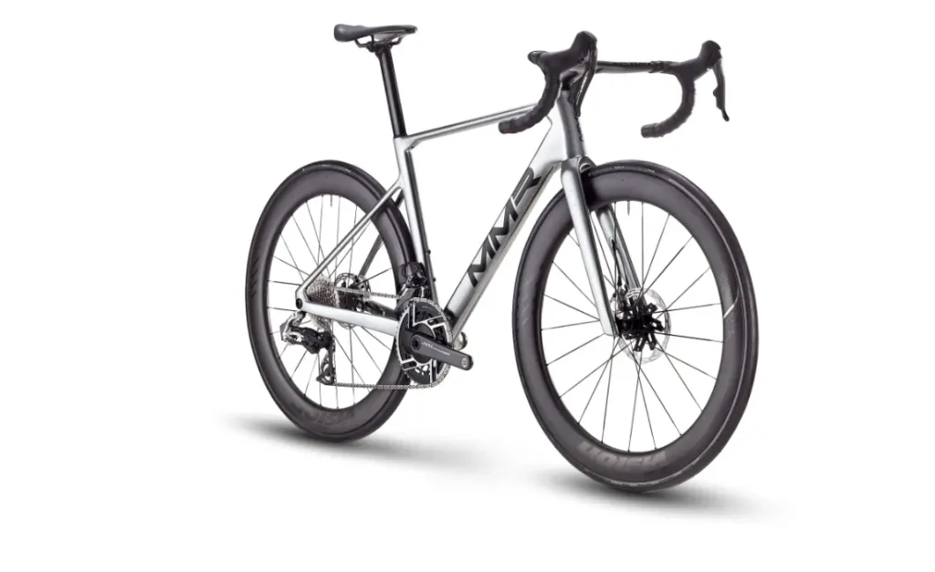 Una moderna bicicleta de carretera MMR Aelion con manillar rebajado, ruedas de sección profunda, frenos de disco y cuadro plateado y negro, sobre fondo blanco.