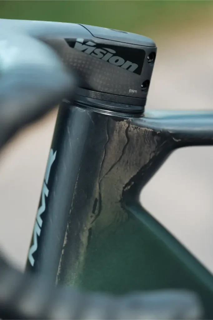 Primer plano de un cuadro de bicicleta con grietas superficiales visibles cerca de la potencia del manillar, con el logotipo "Vision" en la potencia y el diseño distintivo de un modelo MMR Aelion.