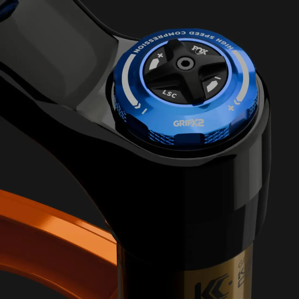 Detalle del dial de ajuste de la horquilla de suspensión FOX 38 2027 para bicicleta de montaña, con ajustes azules de compresión a alta y baja velocidad etiquetados "GRIP2" para un control preciso en Enduro.