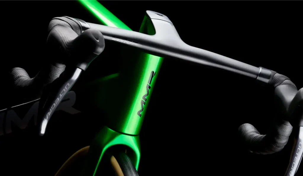Primer plano de un cuadro de bicicleta MMR Aelion verde y manillar negro, destacando el diseño aerodinámico y la marca "MMR", una auténtica bici total con acento asturiano.