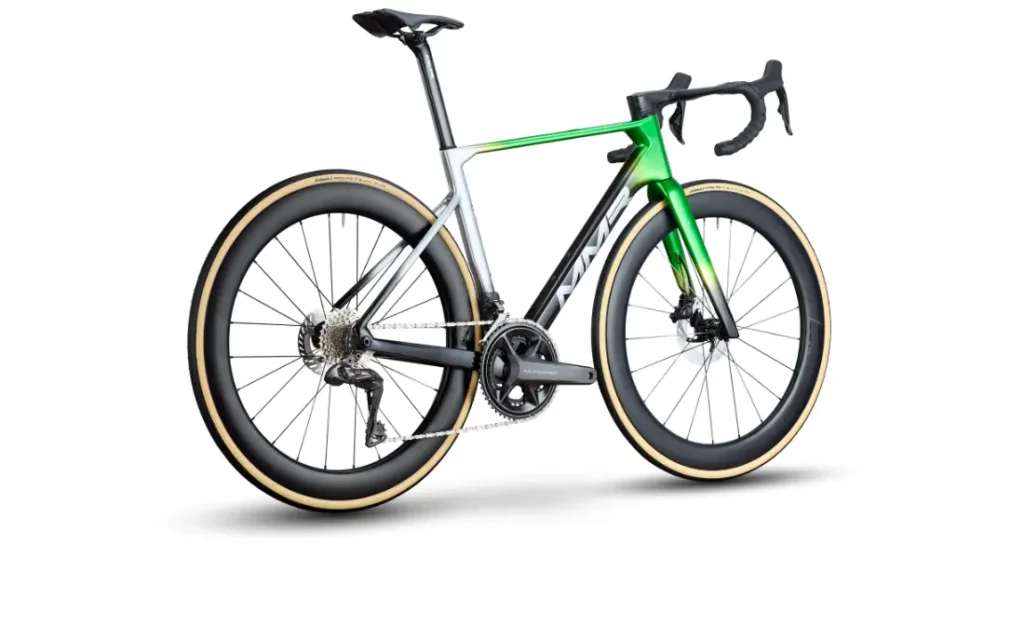 Una moderna bicicleta de carretera, la MMR Aelion, con ruedas de sección profunda, cuadro verde y plateado, manillar caído y un elegante diseño aerodinámico -perfecto para bici total- vista desde un ángulo trasero.
