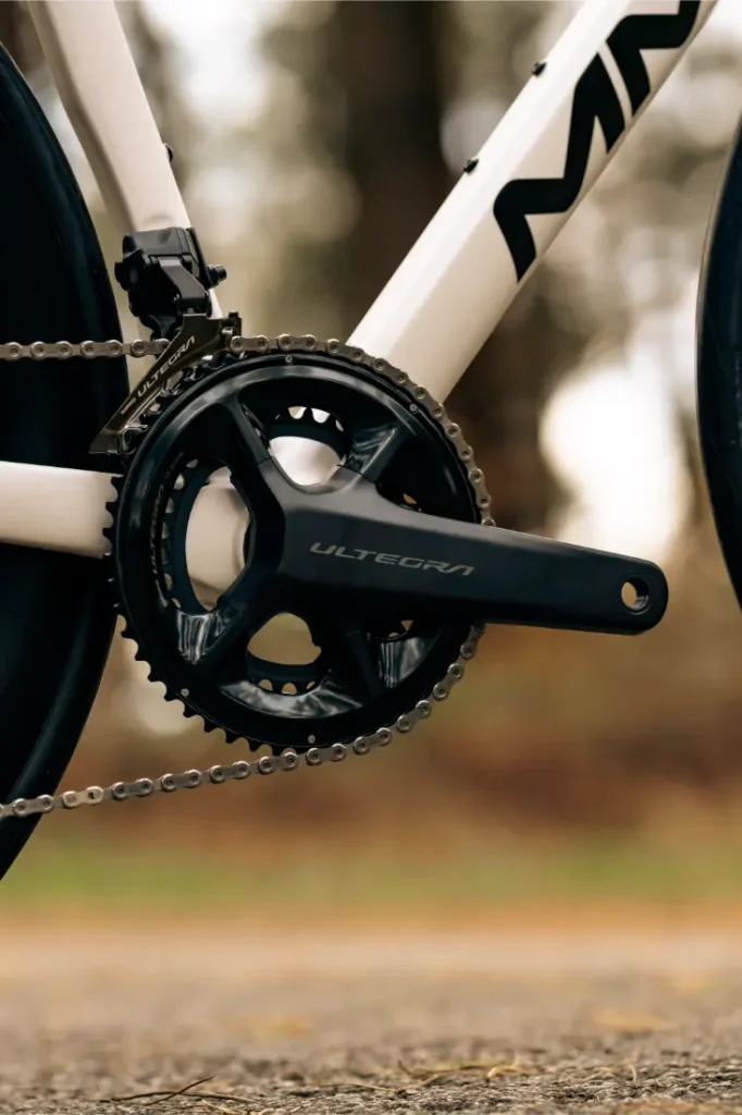 Primer plano de un plato y bielas de bicicleta con la etiqueta "Ultegra", acoplados a un cuadro MMR Aelion SL blanco con parte de la cadena visible: un verdadero escaparate para cualquier entusiasta de la bici total.