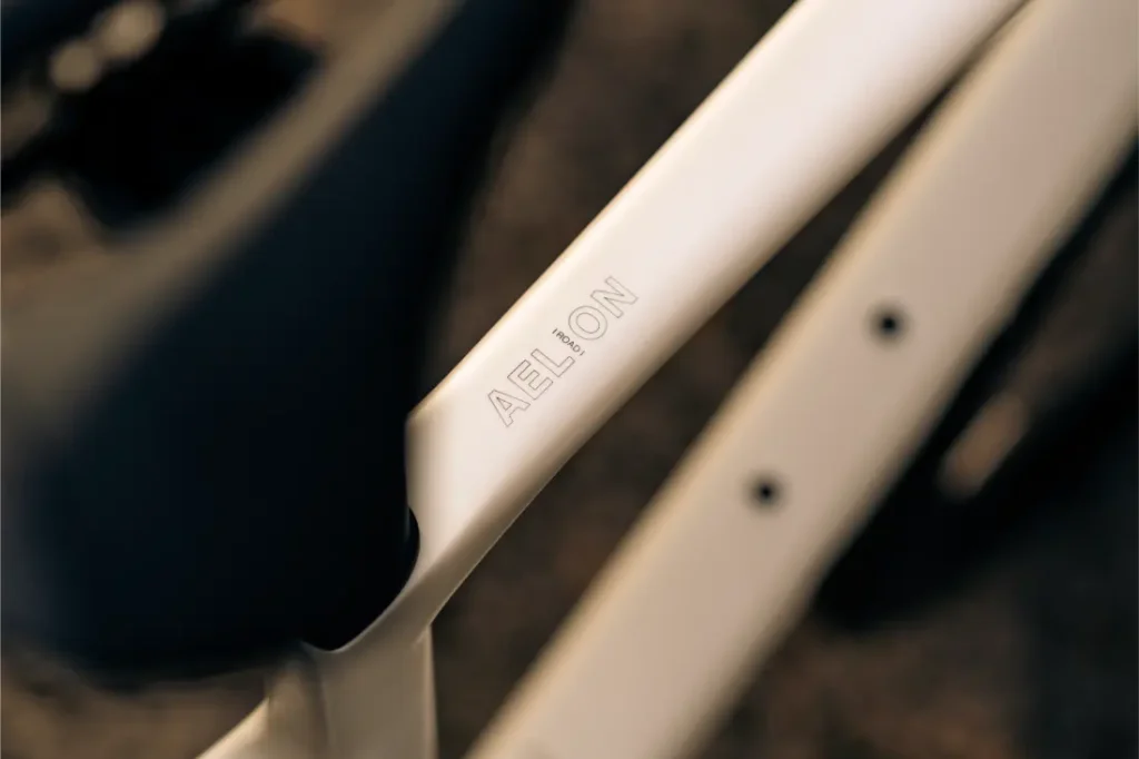 Primer plano de un cuadro de bicicleta Aelion SL con "AELION" grabado en el tubo superior; se ven partes del sillín y del cuadro, que muestran el elegante diseño de esta bici total.