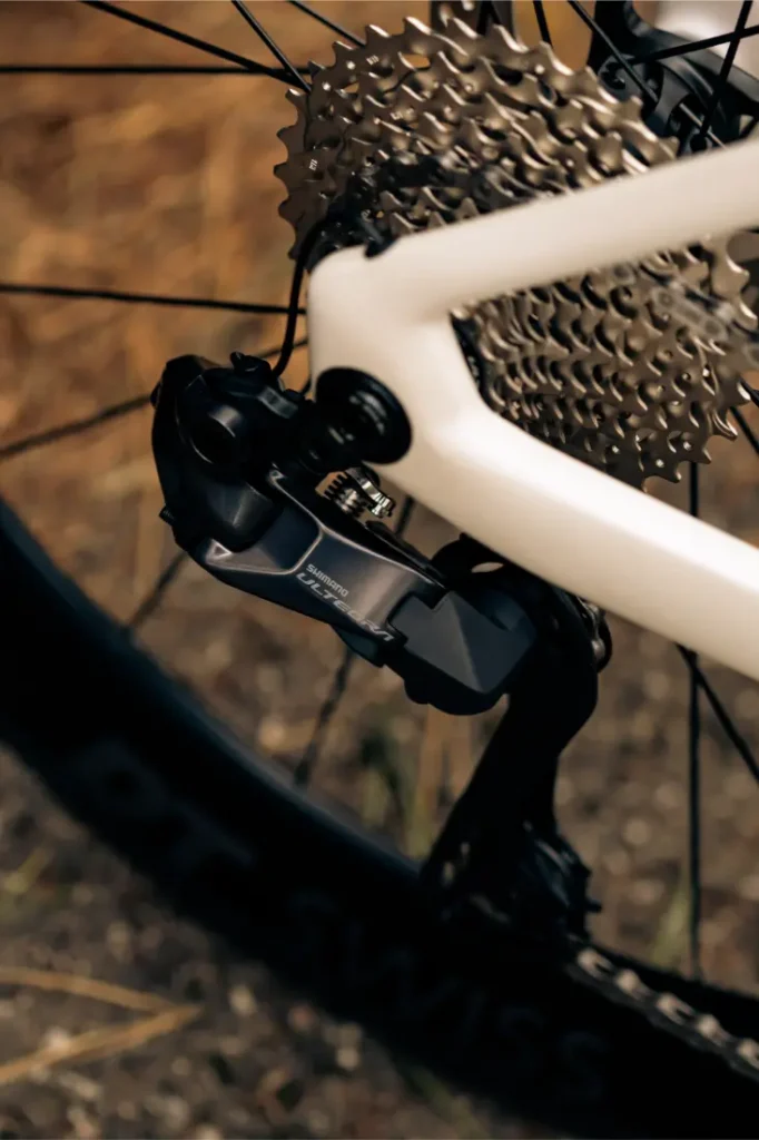 Primer plano del cambio trasero, el casete y la rueda de una MMR Aelion, en el que se muestran en detalle los componentes del engranaje total de la bicicleta con un toque de acento asturiano.