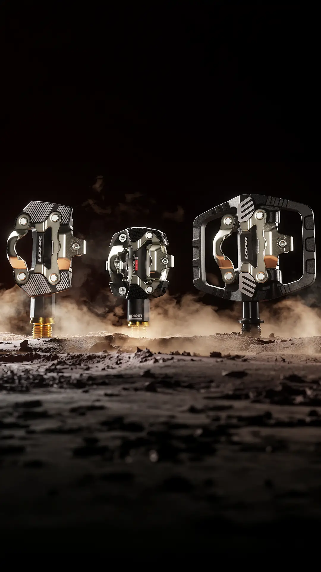Tres pedales LOOK metálicos para Gravel se exponen en posición vertical sobre una superficie rocosa y polvorienta, con un fondo oscuro y una iluminación espectacular, para destacar su lugar en el ecosistema de pedales.