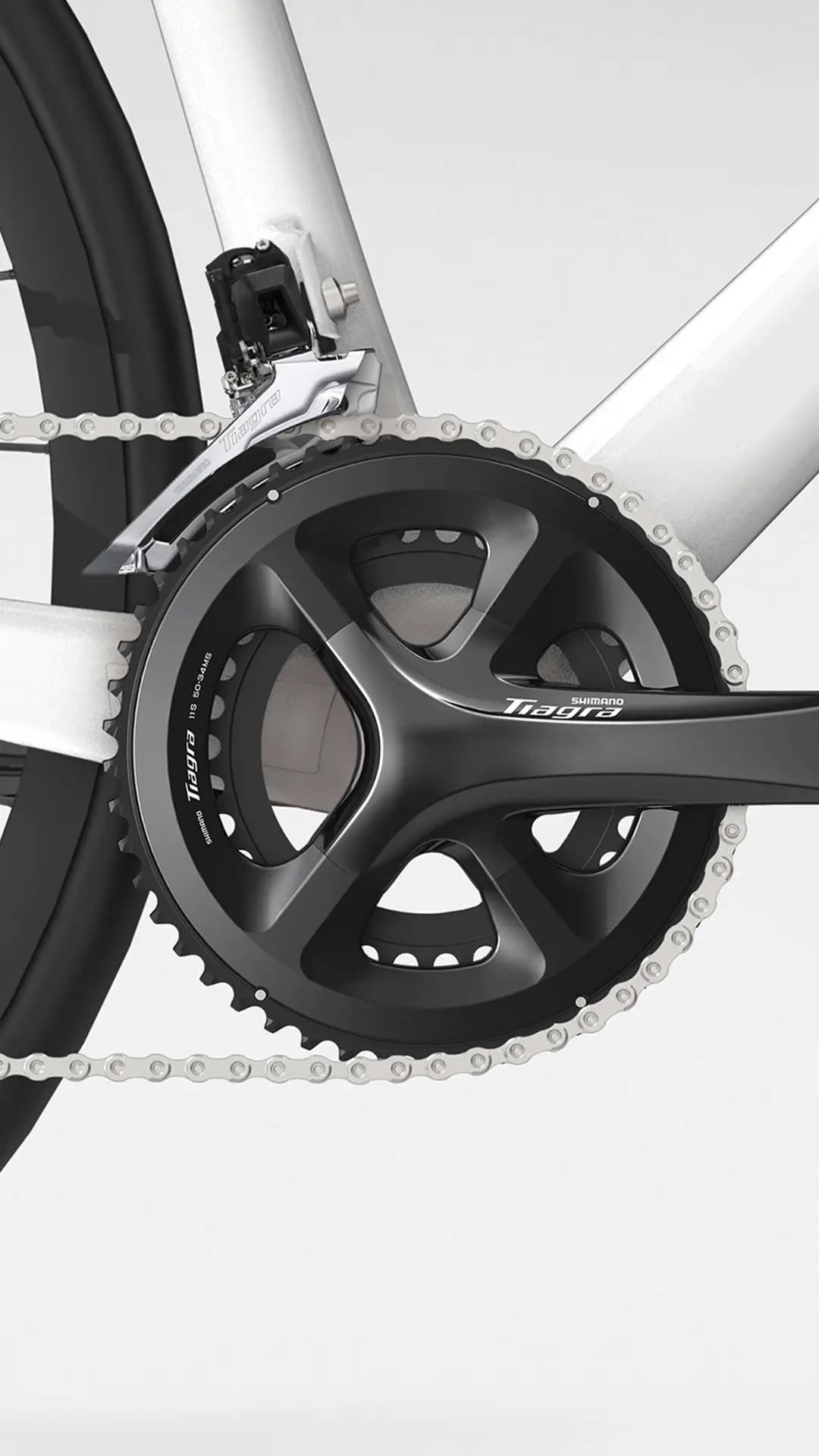 Primer plano de unas bielas y cadena Shimano Tiagra R4000 en un cuadro de bicicleta plateado, mostrando el desviador delantero y parte de la cubierta trasera.