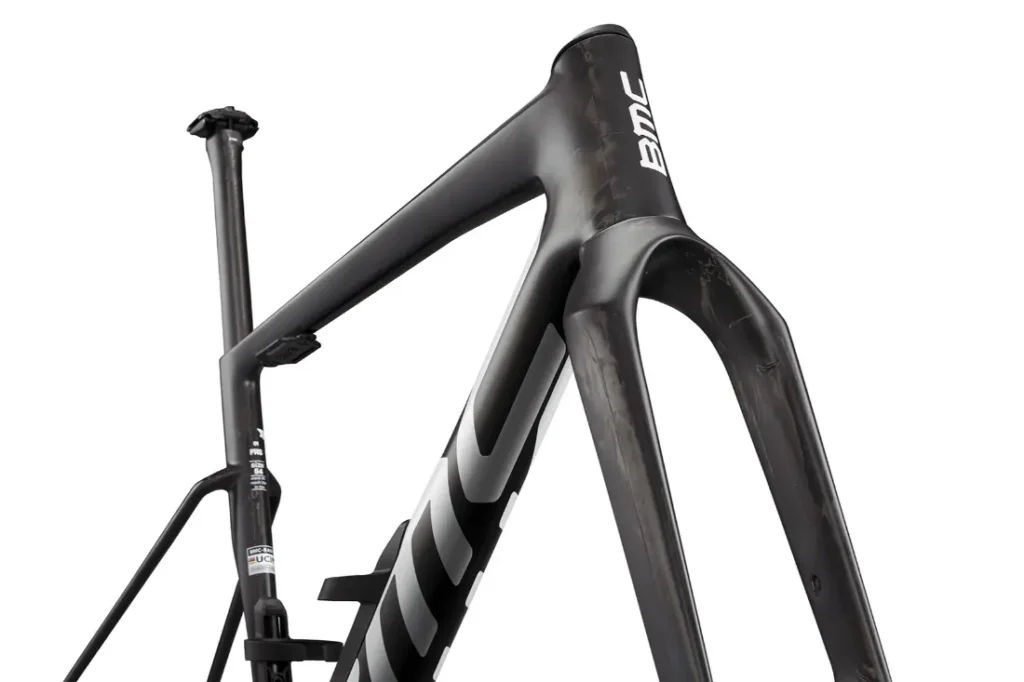 Primer plano del cuadro y la horquilla de una bicicleta BMC Kaius 01 negra, que muestra el tubo de dirección, el tubo diagonal y parte de la tija del sillín sobre un fondo blanco: una bicicleta rápida hecha para el rendimiento.