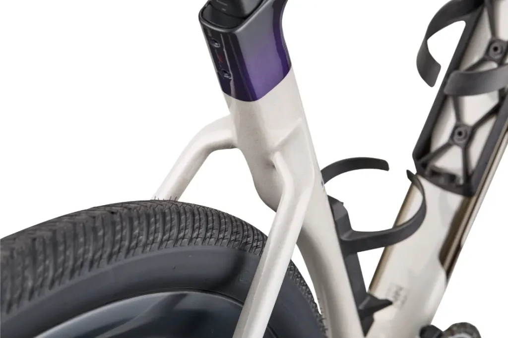 Primer plano de la rueda trasera, el tubo de sillín y el cuadro de una BMC Kaius 01, en el que se aprecian la banda de rodadura de los neumáticos, los portabidones y parte del diseño de la suspensión de la bicicleta rápida.