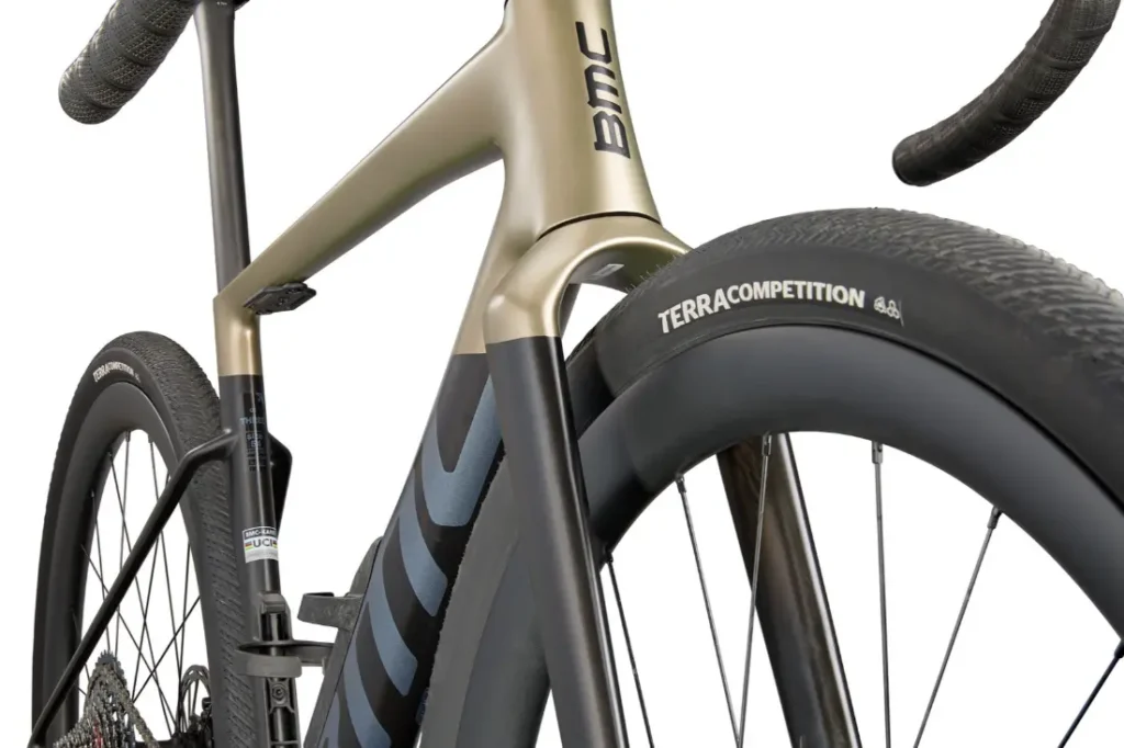 Primer plano de una BMC Kaius 01 bicicleta gravel, destacando la horquilla delantera, el neumático con la etiqueta "Terracompetition", y parte del cuadro y manillar de esta bicicleta rápida.