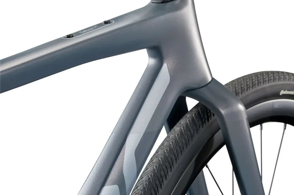 Primer plano de una BMC Kaius 01, una bicicleta rápida con cuadro y cubierta trasera modernos, en la que destacan los tubos lisos y angulosos y la banda de rodadura detallada de la bicicleta moderna.