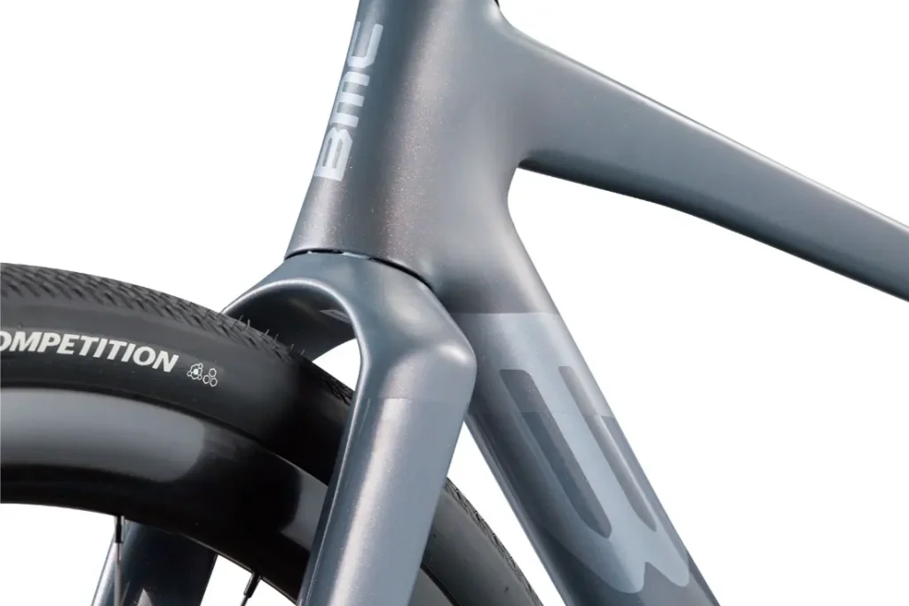 Primer plano de la rueda trasera y el cuadro de la BMC Kaius 01, en el que destacan los tubos lisos y aerodinámicos y un neumático con la etiqueta "Competition": una bicicleta rápida construida para la velocidad.
