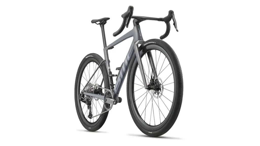 Una BMC Kaius 01 gris mate con manillar rebajado, neumáticos gruesos y frenos de disco se muestra desde un ángulo lateral trasero sobre un fondo blanco: una bicicleta rápida y actual.