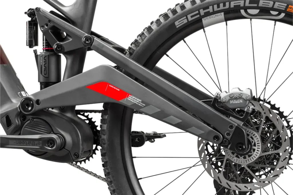 Primer plano de la suspensión trasera, el cuadro y el sistema de frenos de disco de una bicicleta de montaña Rotwild R.EXC, en el que destacan la cubierta Schwalbe y el motor cerca del plato, diseñados para competir al más alto nivel.
