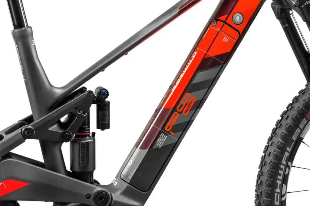 Primer plano de un cuadro de bicicleta de montaña Rotwild R.EXC con amortiguador de suspensión trasera, combinación de colores negro y rojo, ideal para bicicleta de competición, con una vista parcial del neumático trasero, perfecto para los entusiastas del ciclismo serio.