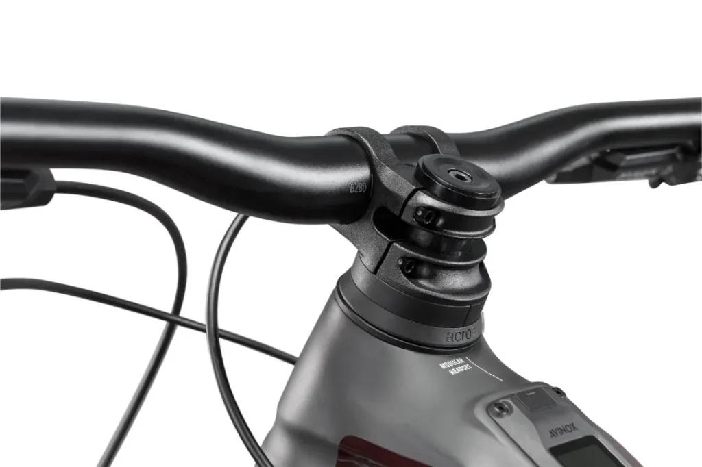 Primer plano de un conjunto de manillar y potencia de bicicleta Rotwild R.EXC con cables visibles y parte de una pantalla digital, en la que se destacan características diseñadas para competir, todo ello sobre un fondo blanco.