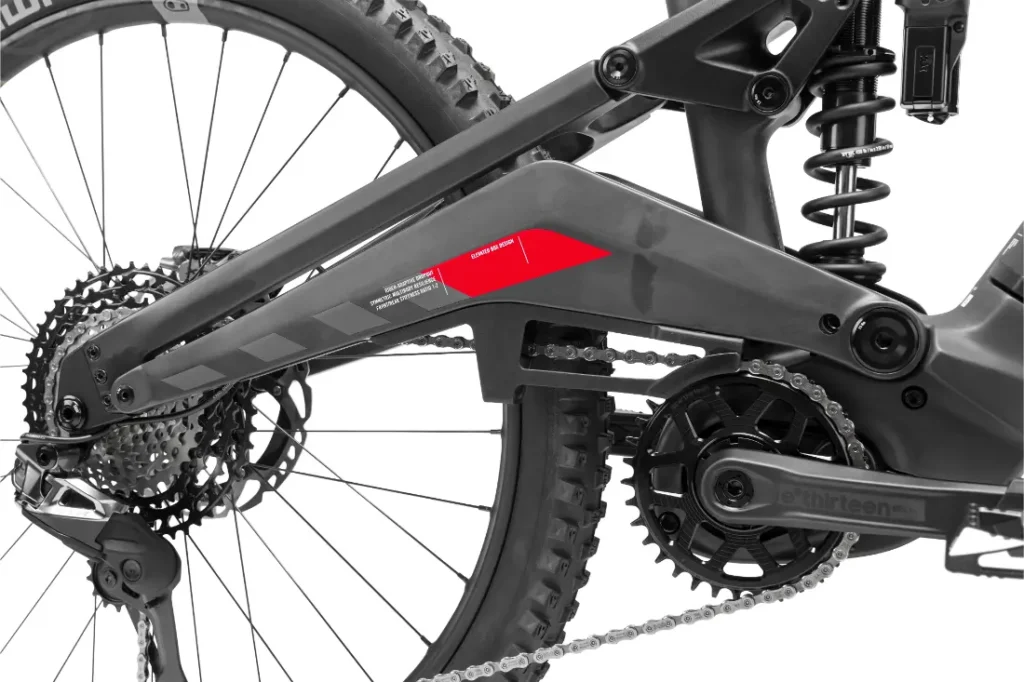 Primer plano de la suspensión trasera y la transmisión de una bicicleta de montaña Rotwild R.EXC, mostrando la cadena, los engranajes y el amortiguador en detalle: ingeniería de precisión lista para competir en cualquier sendero.